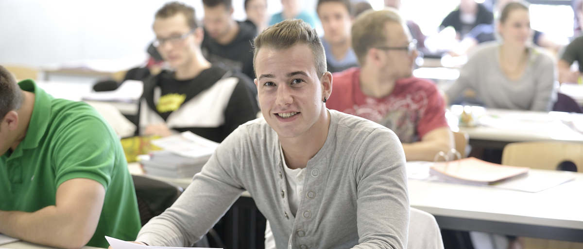 Tischreihen, hintereinander, erste Reihe, Teilnehmer Blick vorne, lächelt, Hintergrund unscharf, Bachelorstudiengang_Unternehmensführung_15585_argum
