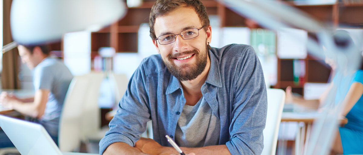 Büro, Mann, Arbeitsplatz, Arbeiten, junger Mann, Laptop, Statistik, Schreibtisch, Stift, erfolgreich, Lächeln, freundlich, kompetent, people, person, businesspeople, lifestyle, male, man, businessman, woman, female, business, contemporary, corporate, work, executive, job, employment, busy, career, young, adult, foreground, background, workplace, document, handsome, confident, successful, Caucasian, positive, casual, laptop, occupation, data, information, planning, expertise, bearded, eyeglasses, sitting, pc, looking, happy, smiling, profession, professional, pen, toothy, smiley, attractive, masculine