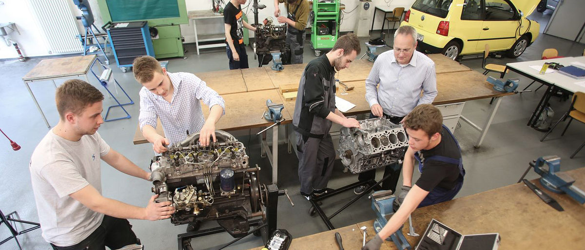 Lehrwerkstatt, ÜLU, Kfz, Unterricht, Ausbildung, Lehrlinge, Männer, Ausbildungsmeister, Gruppenfoto, Auto, Hebebühne, Messgeräte, Werkbank