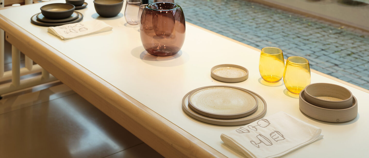 Blick aus der Galerie mit Kunstobjekten aus der Ausstellung Tischkultur mit Gläsern, Karaffe, Schüsseln, Tassen, Tellern