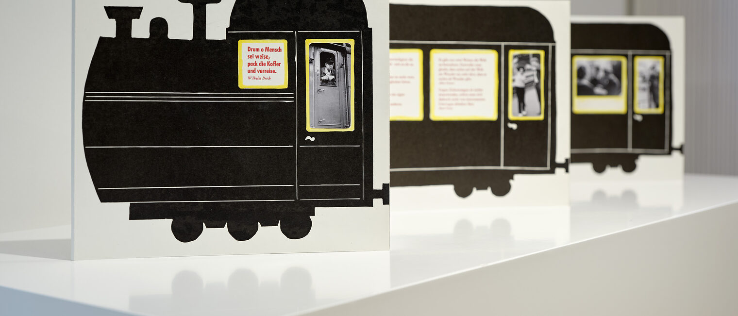 Drei Aufsteller in Schwarz-Weiß, die zusammen eine nostalgische Lokomotive darstellen in der Reise-Ausstellung der Galerie.