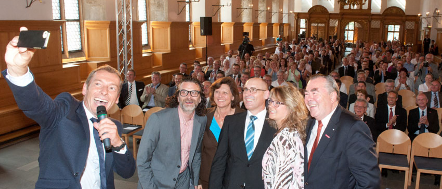 Moderator Markus Othmer schießt ein Selfie vom Tag des Handwerks mit Joachim Groha, Ministerin Ilse Aigner, Wilhelm Puchta, Jasmin Breitschwert und BHT-Präsident Heinrich Traublinger (v.l.n.r.).